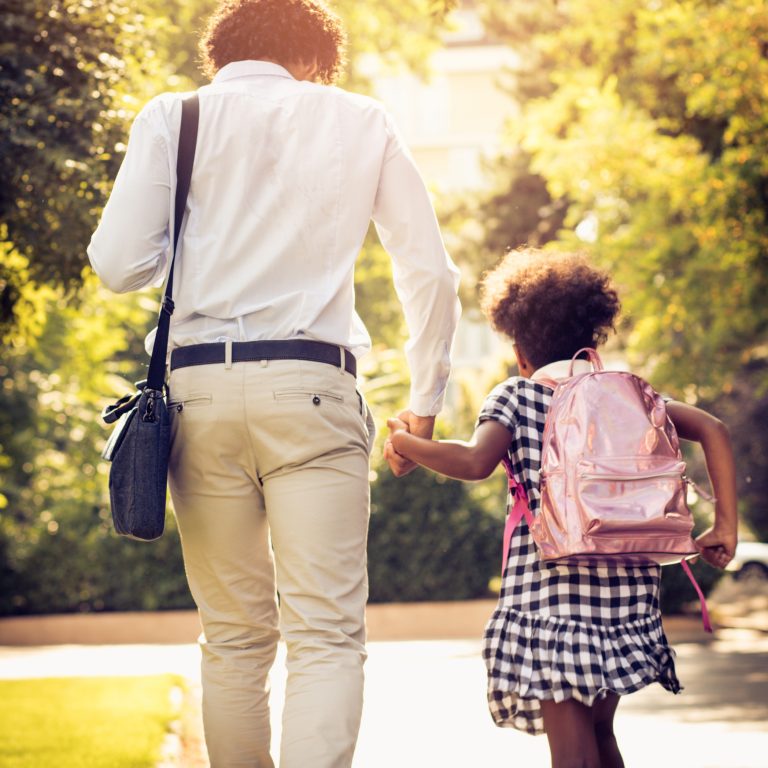 Father and daughter running through park.