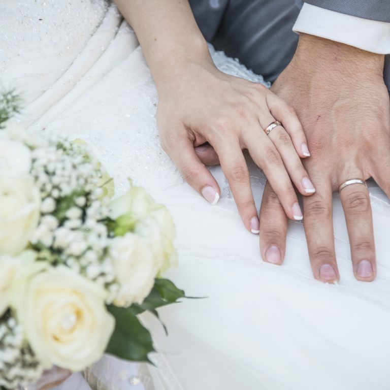 hands of a just married couple with the wedding rings and bouquet