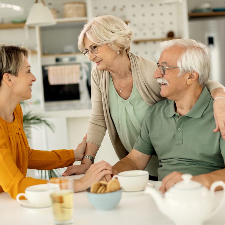 Happy woman visiting her senior parents and communicating with them at home.