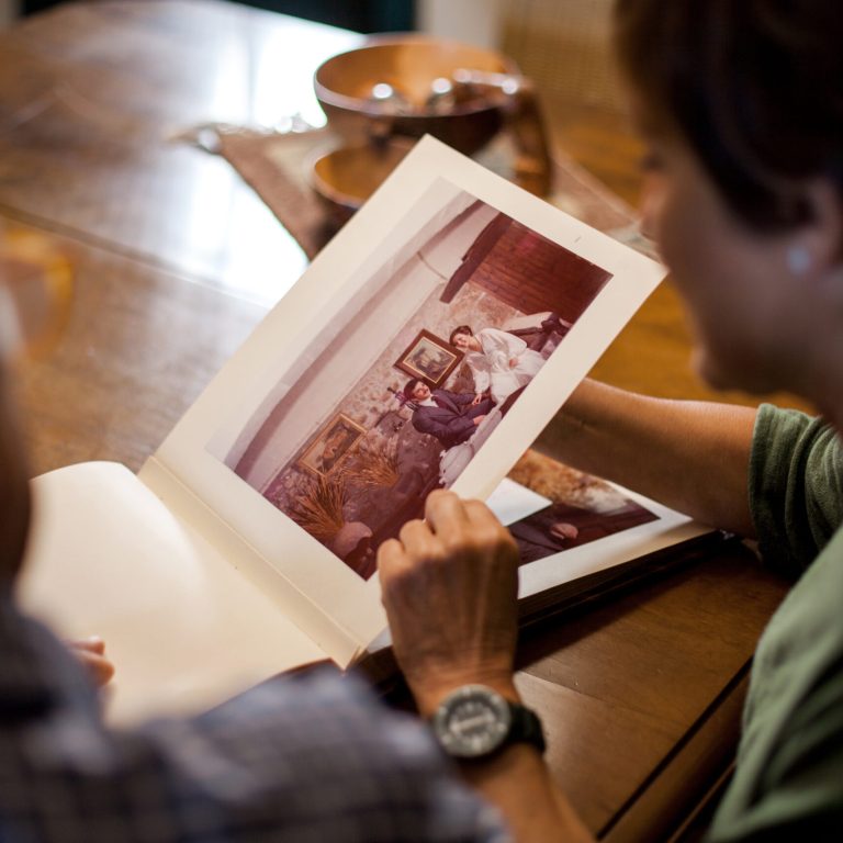 First point of view of a senior man and woman looking at a old wedding photo album.