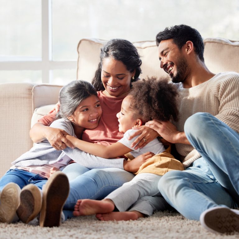 Affectionate and loving mixed race family sitting together. Happy family with two daughters hugging their mother and bonding at home. Two little girls enjoying a happy childhood with mom and dad