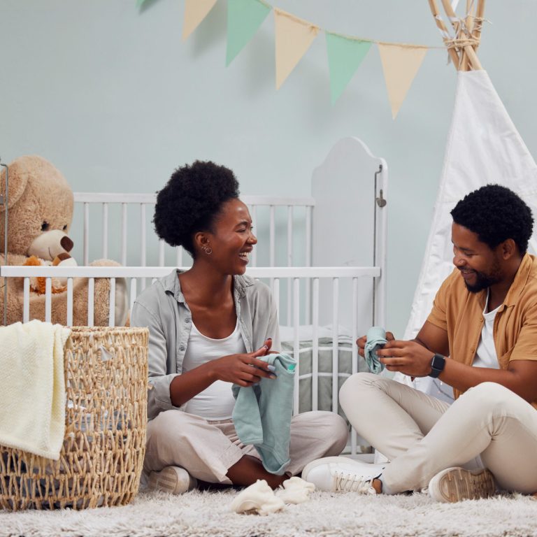 Pregnant and baby room and couple happy to prepare for a family home and folding clothes. Man and woman together talking about excited pregnancy future
