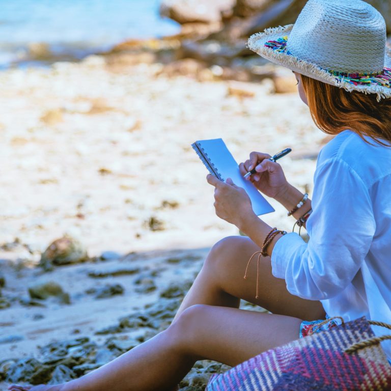 Side View Of Woman Planning While Sitting At Beach