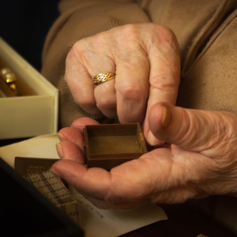 Old lady picking out jewellery from a jewellery box.