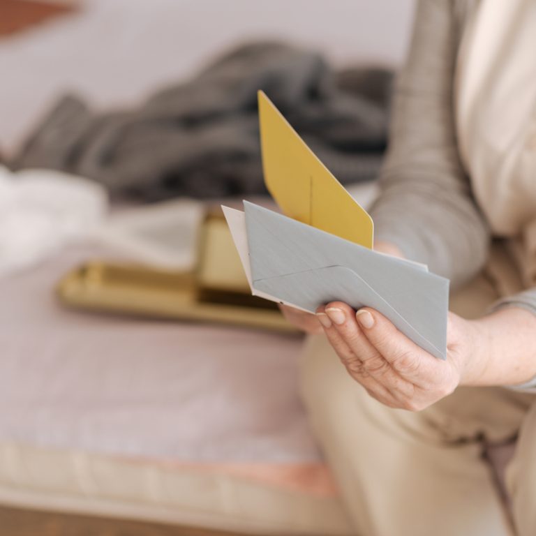 My mail. Close up of envelopes being held by a nice pleasant aged woman while sitting on the bed